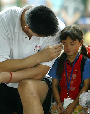 Chinese basketball star and Houston Rockets center Yao Ming (L) wipes tears for a Chinese AIDS orphan Zhang Yun during an HIV/AIDS awareness event at the Tsinghua University in Beijing July 17, 2005. Yao returned to China this week to take part in the NBA "Basketball without Borders" outreach event.