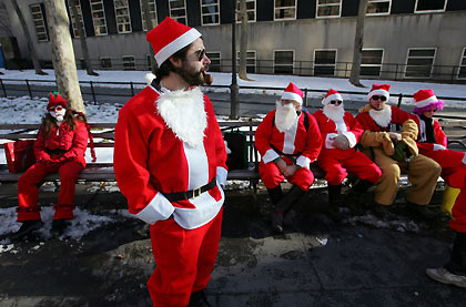Santas wait for more Santas to gather in Brooklyn, New York December 10, 2005. They were participating in the annual New York SantaCon, which involves hundreds of people in cheap Santa suits walking around the city, singing naughty carols, drinking, and generally spreading holiday cheer and mayhem.