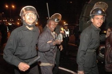 Egyptian riot police arrest an injured Sudanese man in a Cairo public square December 30, 2005.