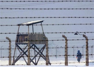 A person walks past a guard tower at the former Nazi-run Auschwitz-Birkenau concentration camp in Brzezinka, Poland, on Friday, Jan. 27, 2006.