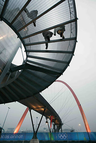 Athletes returning to their village in the Olympic Park descend a circular staircase from a walkway that passes through a giant arch (below) in Turin, Italy February 8, 2006. The Torino 2006 Winter Olympic Games get underway February 10.