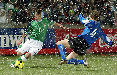 Estonia's Raio Piiroja dives in to tackles Northern Ireland's Peter Thompson during an international friendly soccer match at Windsor Park in Belfast, Northern Ireland, March 1, 2006. [Reuters]