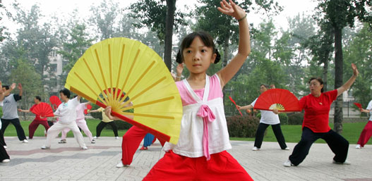 Li Kexin, an eight-year-old girl, performs fan-dance with elderly women at a park where activities are held to mark a two-year-countdown to the 2008 Olympic Games in Beijing, August 8, 2006.