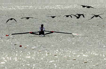 Wildfowls fly over a silhouetted competitor as he rows during a heat at the World Rowing Championships in Eton, southern England, August 21, 2006. 