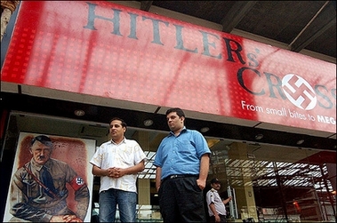 Pedestrian walk past a newly-opened restaurant called "Hitler's Cross," 18 August 2006 on its opening day, in the outskirts of India's financial hub of Mumbai. A leading Jewish group expressed outrage over the Hitler-themed restaurant accusing the owners of trivialising the Holocaust