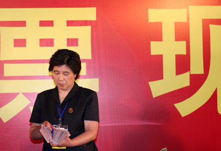 A notary official counts the vote after a voting on the housing demolition and compensation policy at Jiuxianqiao sub-district in Chaoyang District of Beijing, June 9, 2007. Some 3,711 families, about 57% of the 5,473 families, cast their votes on Saturday, with 2,451 votes for and 1,228 votes against the demolition and compensation plan. Thirty-two votes were invalid.