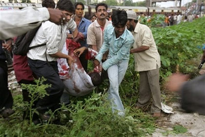 Rescue workers carry an injured passenger after a bomb blast at the Mahim railway station, in Bombay, India, Tuesday, July 11, 2006. Eight explosions ripped through packed commuter trains during rush hour Tuesday in India's commercial capital, killing nearly 150 people and injuring another 439 in what officials said was a well-coordinated bomb attack by terrorists. (